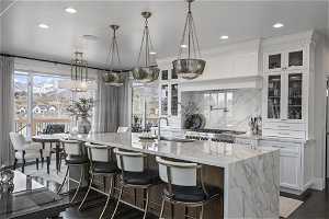 Kitchen featuring white cabinets, a kitchen breakfast bar, a kitchen island with sink, and light stone counters