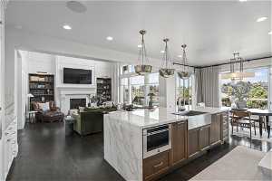 Kitchen featuring an island with sink, hanging light fixtures, dark hardwood / wood-style flooring, and sink