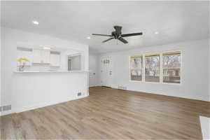 Living room with ceiling fan and light hardwood / wood-style flooring