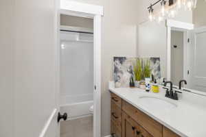 Full bathroom with tile floors, toilet, vanity, and washtub / shower combination