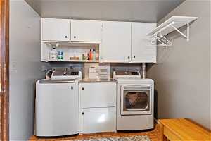 Laundry area featuring light parquet flooring, washer hookup, cabinets, and washing machine and clothes dryer
