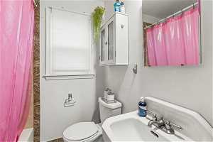 Full bathroom with shower / bath combo with shower curtain, toilet, and sink