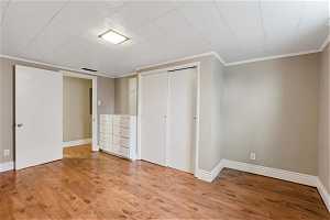 Unfurnished bedroom with a closet, crown molding, and light wood-type flooring