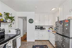 Kitchen with white cabinets, stainless steel appliances, and light tile floors