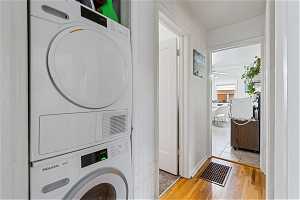 Clothes washing area with light tile floors, ceiling fan, and stacked washer and dryer