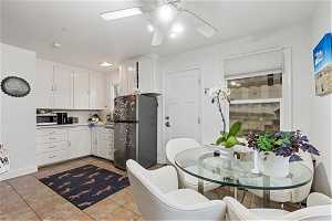 Kitchen featuring white cabinets, light tile flooring, stainless steel appliances, and ceiling fan