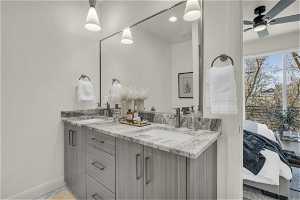Bathroom featuring vanity with extensive cabinet space, dual sinks, and ceiling fan