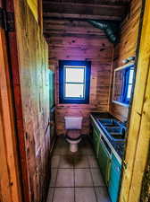 Bathroom featuring wood walls, tile flooring, and toilet