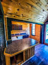 Kitchen featuring wooden walls, dark hardwood / wood-style flooring, wood ceiling, and vaulted ceiling