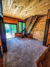 Spare room featuring dark colored carpet and wooden ceiling