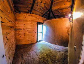 Empty room featuring wood walls, wooden ceiling, and vaulted ceiling