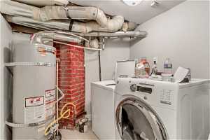 Washroom with water heater, light hardwood / wood-style floors, and washer and clothes dryer