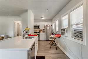 Kitchen featuring white cabinets, light hardwood / wood-style floors, sink, and stainless steel appliances