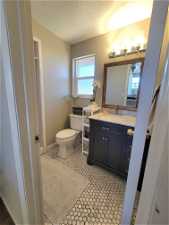 Bathroom featuring toilet, tile floors, a textured ceiling, and vanity