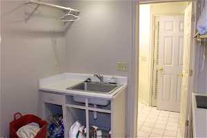 Laundry room features lots of shelving and a sink.