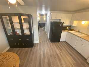 Kitchen with ceiling fan, white cabinets, sink, and black fridge