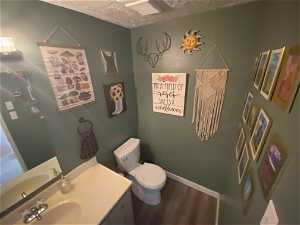 Bathroom with hardwood / wood-style flooring, vanity, a textured ceiling, and toilet