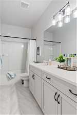 Full bathroom featuring tile floors, shower / bath combination with curtain, toilet, and vanity