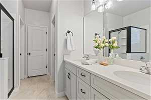 Bathroom with double vanity, tile floors, and a shower with door