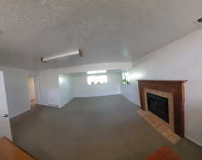 Unfurnished living room with a textured ceiling, carpet flooring, and a fireplace