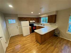 Kitchen light hardwood / wood-style floors, ventilation hood, and white fridge