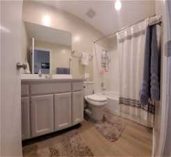 2nd bathroom in Hallway upstairs, with vanity, shower / bath combination with curtain, wood-type flooring, and toilet