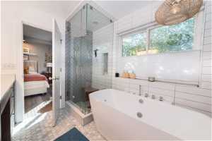 Bathroom with vanity, plus walk in shower, tile floors, and tile walls