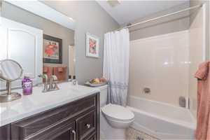 Full bathroom with toilet, large vanity, shower / bath combo, a textured ceiling, and tile floors