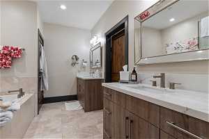Bathroom with tiled bath, tile floors, double sink, and large vanity