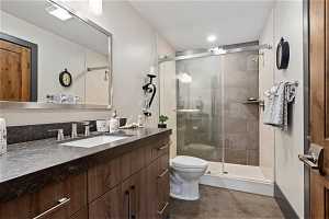 Bathroom featuring vanity, tile flooring, a shower with door, and toilet