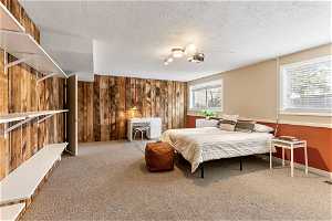 Carpeted bedroom with a textured ceiling and wood walls