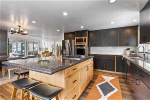 Kitchen featuring a kitchen island, stainless steel appliances, tasteful backsplash, a kitchen bar, and light brown cabinetry