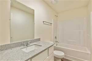 Full bathroom with tub / shower combination, large vanity, and toilet