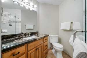 Bathroom featuring an enclosed shower, vanity, toilet, and tile floors