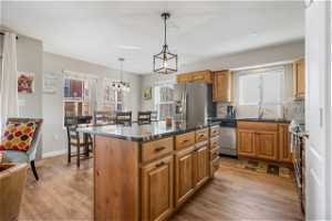 Kitchen with light hardwood / wood-style floors, a center island, stainless steel appliances, decorative light fixtures, and a chandelier