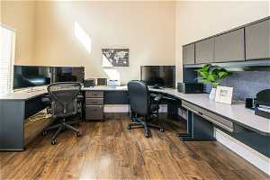 Office with built in desk, a high ceiling, and dark hardwood / wood-style floors