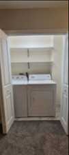 Laundry room with washer and clothes dryer and light colored carpet