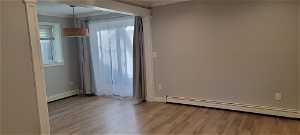 Unfurnished room featuring a baseboard radiator, light wood-type flooring, and crown molding