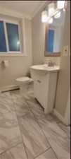 Bathroom featuring toilet, vanity with extensive cabinet space, crown molding, tile floors, and a baseboard radiator