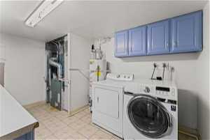 Washroom with light tile floors, cabinets, water heater, and separate washer and dryer