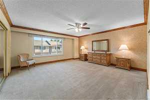 Unfurnished bedroom with a textured ceiling, crown molding, ceiling fan, and light colored carpet