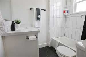 Full bathroom featuring tiled shower / bath combo, vanity, tile flooring, and toilet