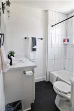 Full bathroom with tiled shower / bath, toilet, tile floors, and vanity