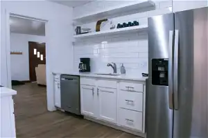 Kitchen with sink, dark hardwood / wood-style flooring, stainless steel appliances, tasteful backsplash, and white cabinetry