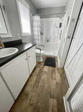 Bathroom with curtained shower, toilet, hardwood / wood-style floors, and vanity