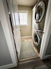 Clothes washing area with dark tile flooring and stacked washer and dryer