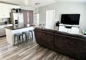 Living room with vaulted ceiling and light wood-type flooring