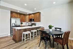 Kitchen with stainless steel appliances, kitchen peninsula, a breakfast bar area, light wood-type flooring, and sink