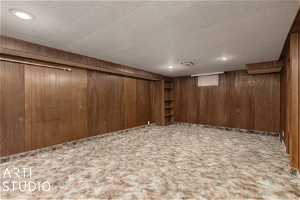 Basement with carpet flooring and wooden walls
