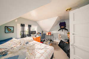 Carpeted bedroom featuring lofted ceiling